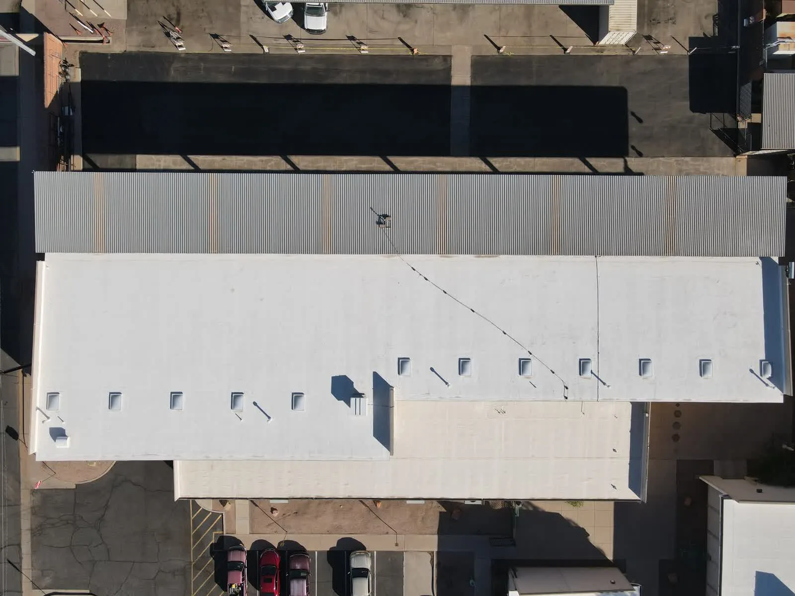 Aerial drone view of commercial building rooftop and parking area