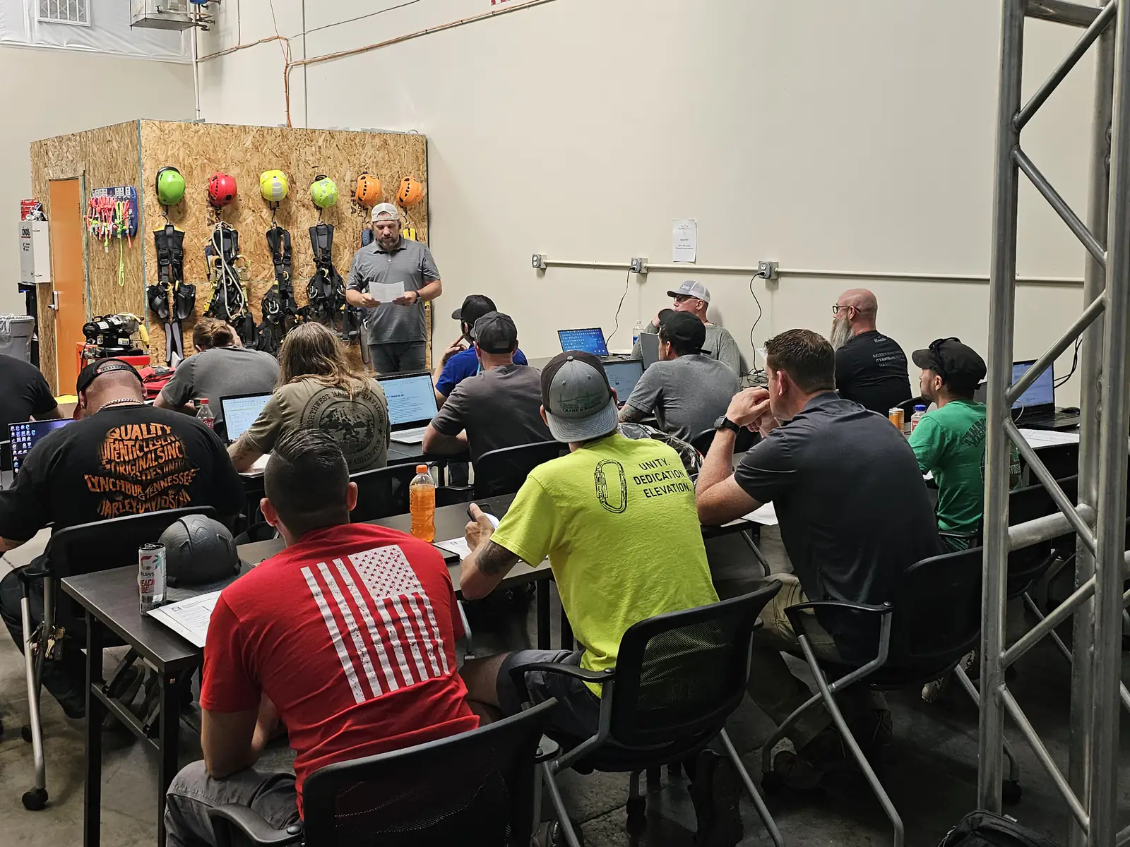 Instructor teaching a class at PSTC in front of the helmet and harness wall