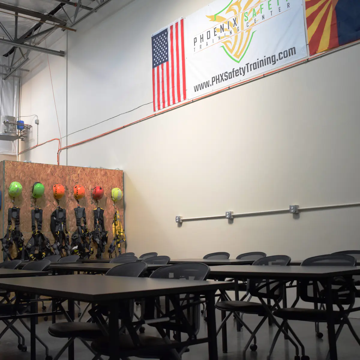 Yosemite Workshop classroom tables under the PSTC banner, beside the helmet and harness wall
