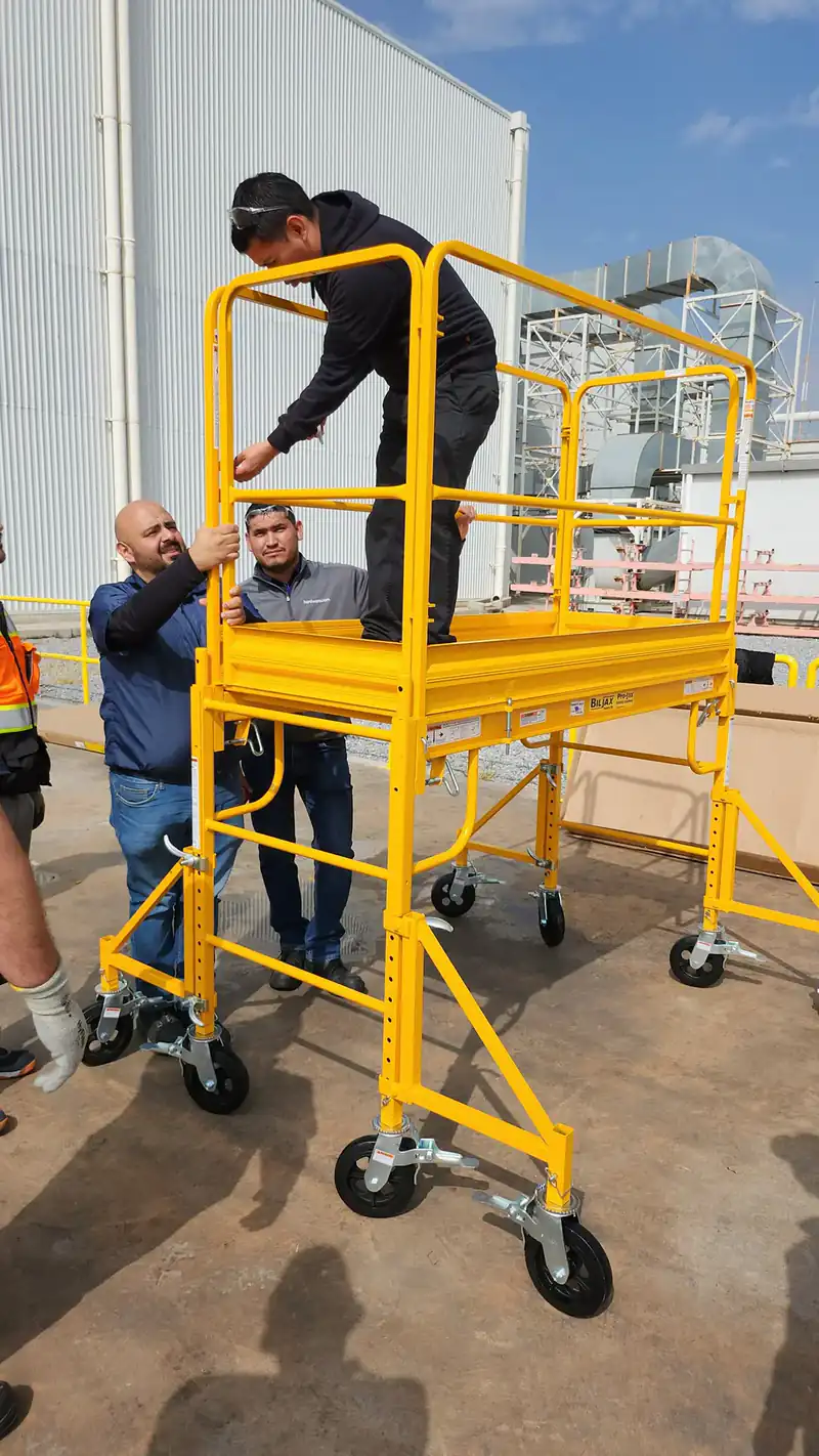 Trainees assembling a yellow rolling scaffold during a training exercise